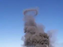 A smoke stack with black smoke coming out of it.
