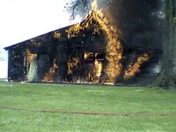 A house on fire with grass around it