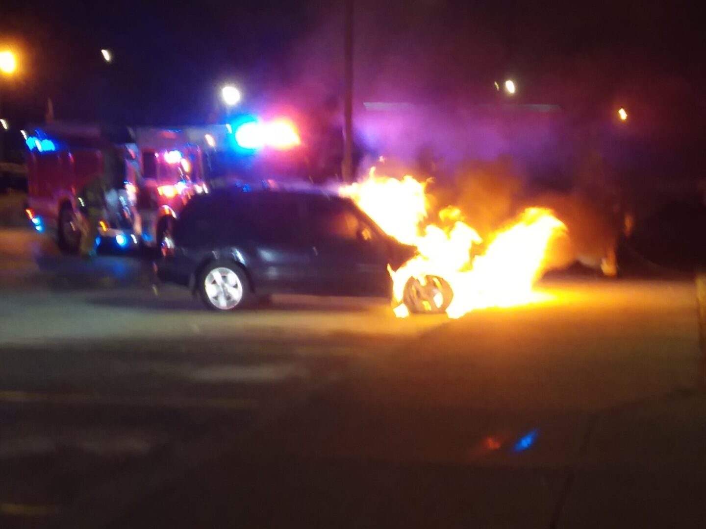 A car on fire in the middle of night.
