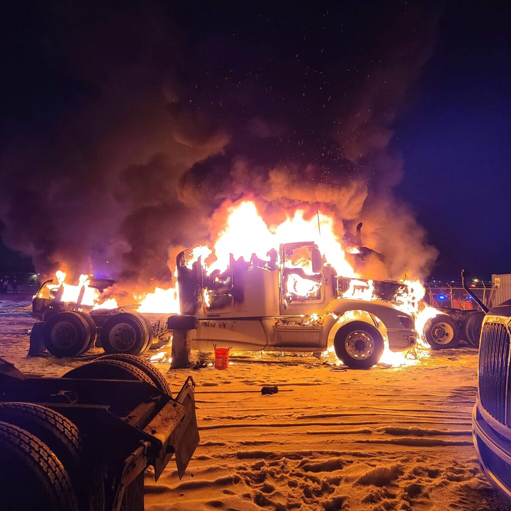 A truck that is on fire in the sand.